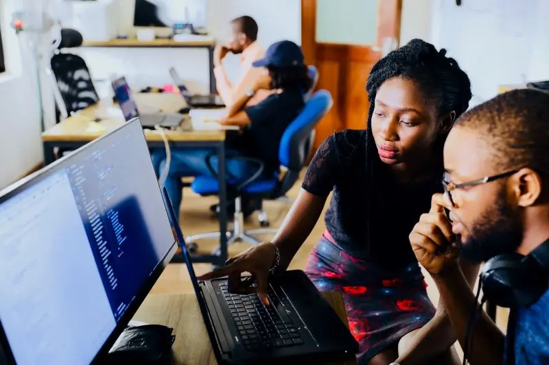 an African lady showing a man something on a computer