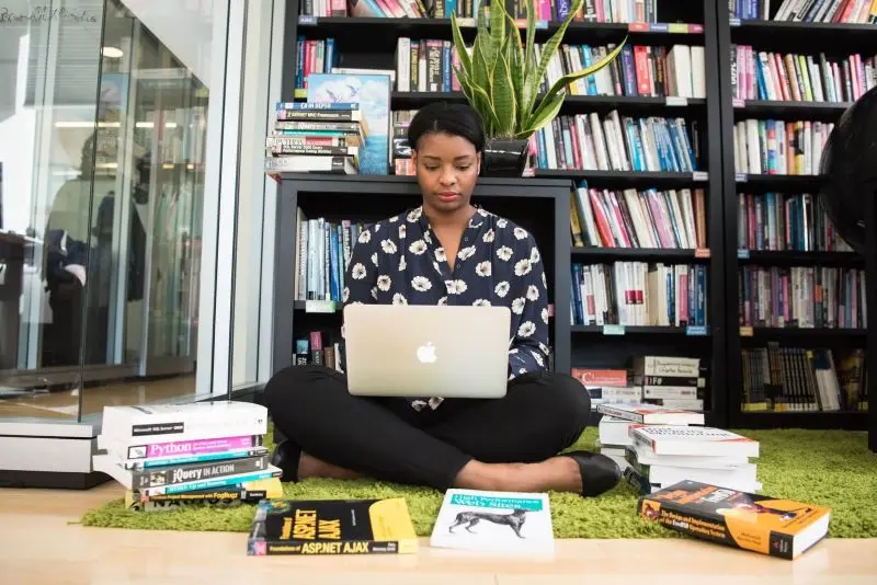 a young lady sitting on the floor and working on a computer
