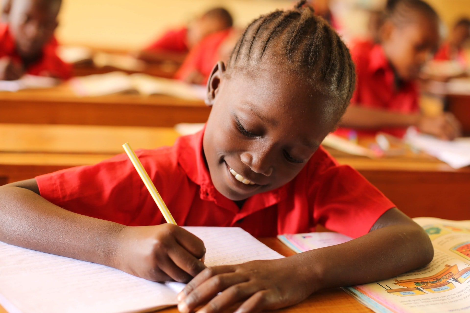 a smiling African girl child writing in her book