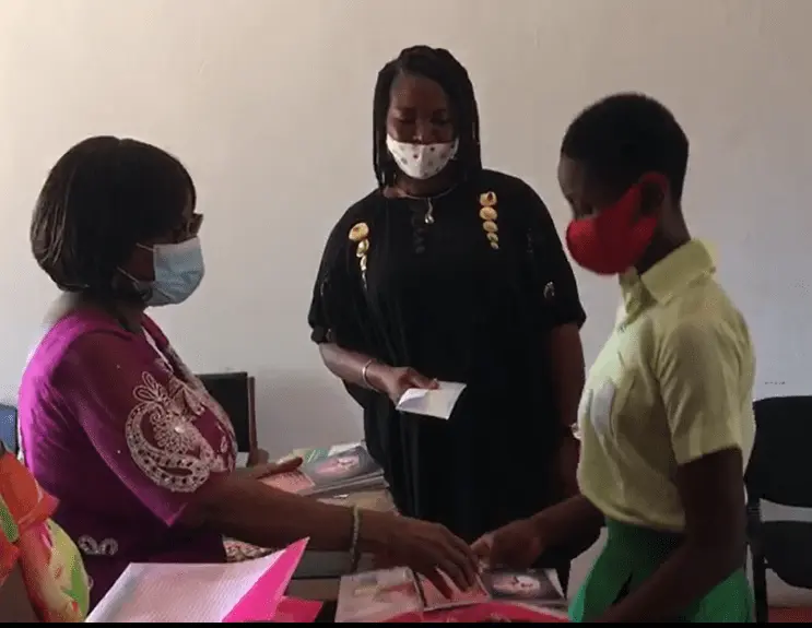a secondary school girl receiving financial aid from the founder of EFAW